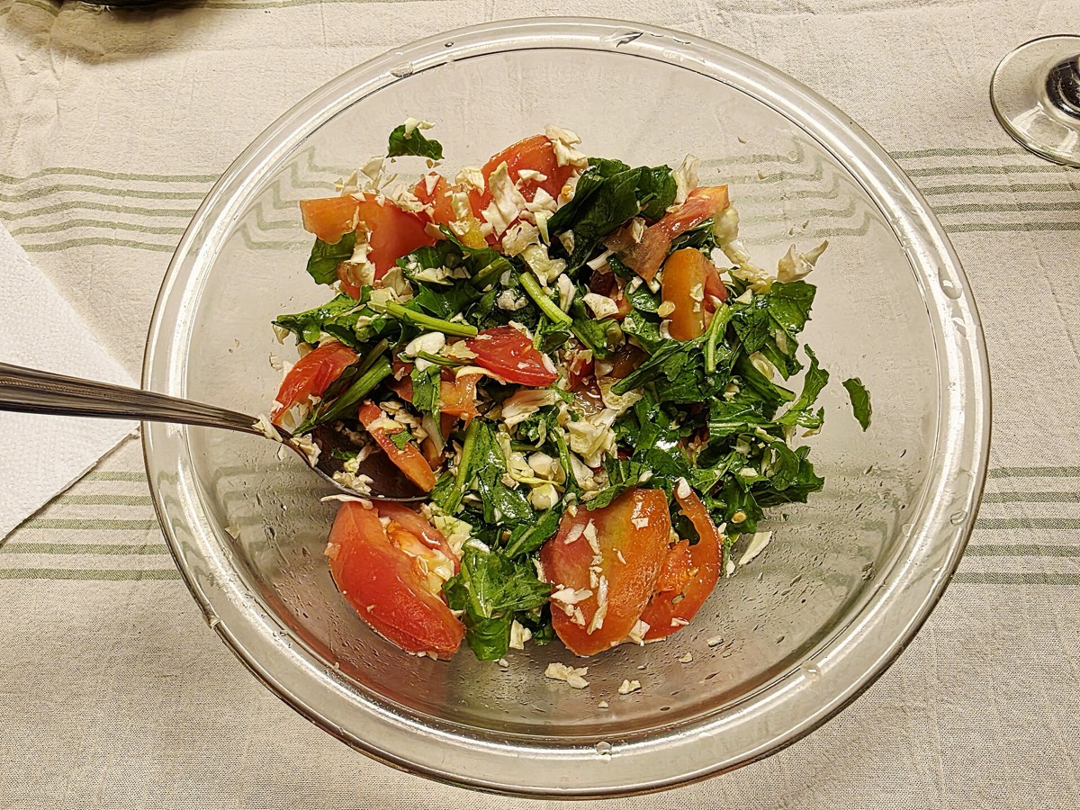 Arugula, cabbage and tomato salad in a glass bowl