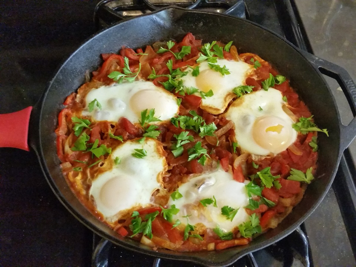 Shakshuka with five eggs in a cast-iron pan